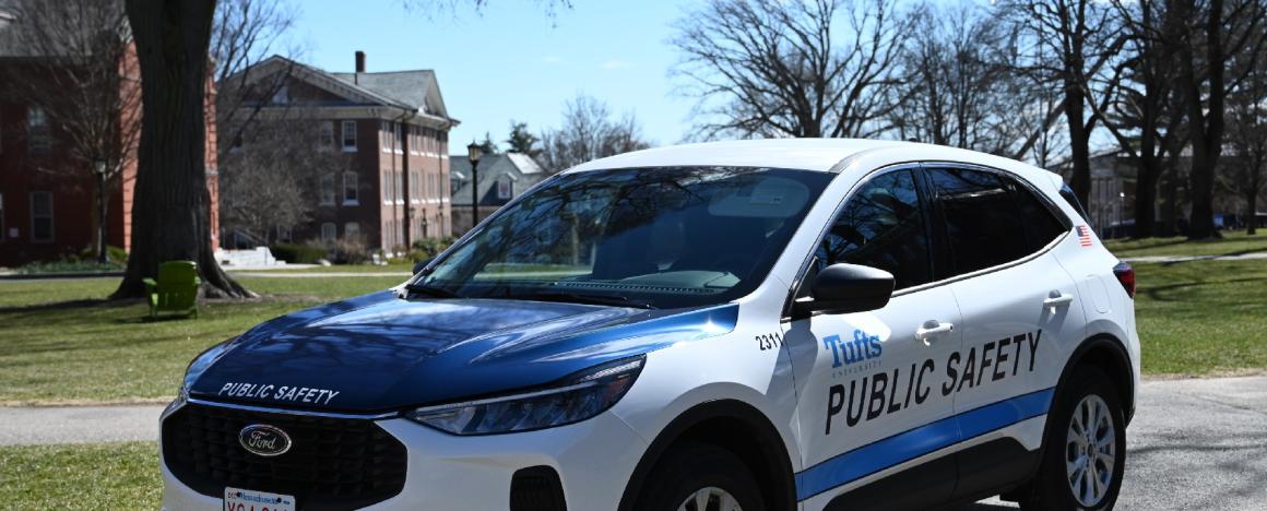 A public safety vehicle with a blue hood is parked on a college campus