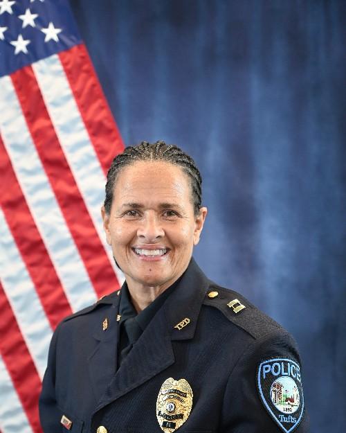 A female police officer smiling in front of an American flag