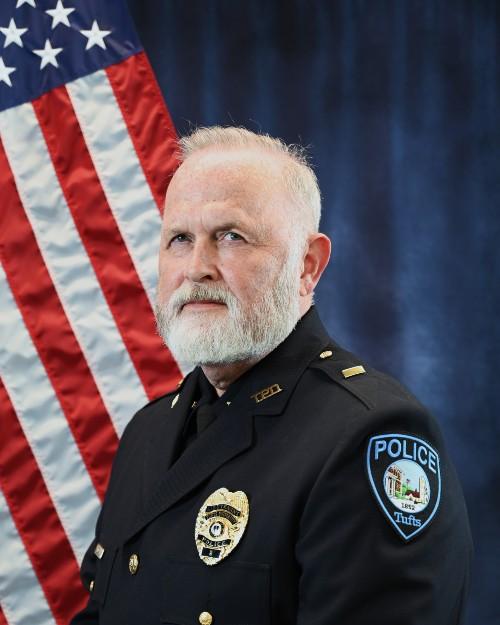 A police officer smiling in front of an American flag