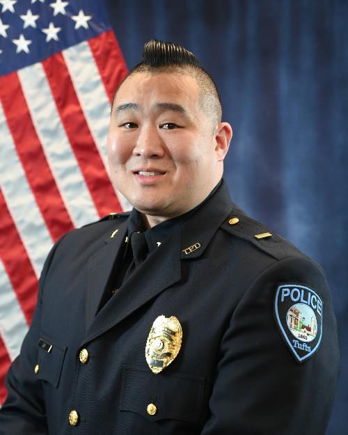 A police officer smiling in front of an American flag