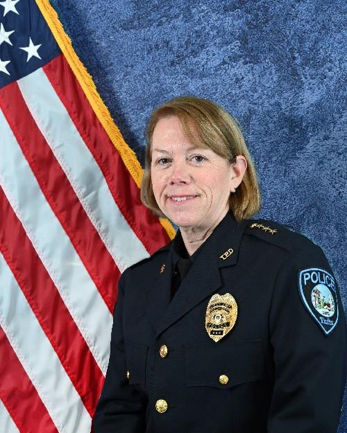 A police officer smiling in front of an American flag