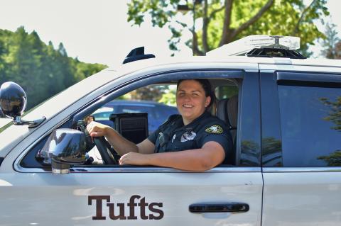 Tuft's Police Officer sitting in driver seat of their patrol vehicle smiling