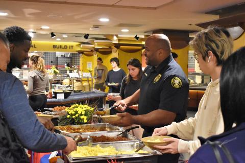 Students and TUPD officer serving himself food from a buffet station.