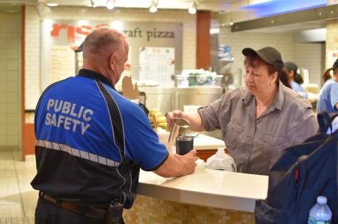 A kitchen worker pour coffee into a security officer's cup
