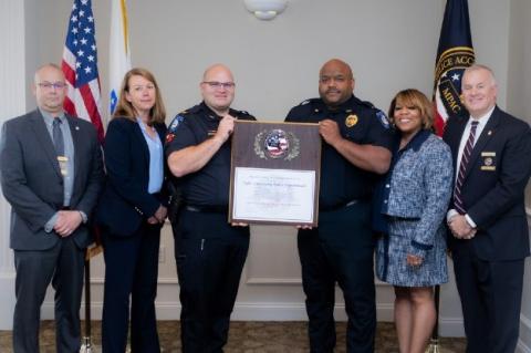 A group of people and police officers stand holding a plaque in the center