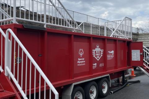 A red trailer containing water with white railings and a cloudy sky